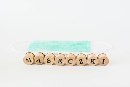 Words written with wooden blocks with black letters laying on protective surgical masks "Maseczki" means "masks" in polish.の写真素材