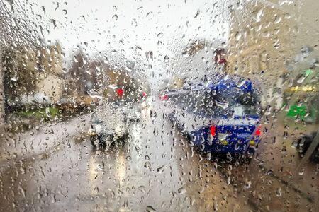Close up of raindrops on wet glass window of a tram and the view to the street and traffic on a rainy dayの写真素材