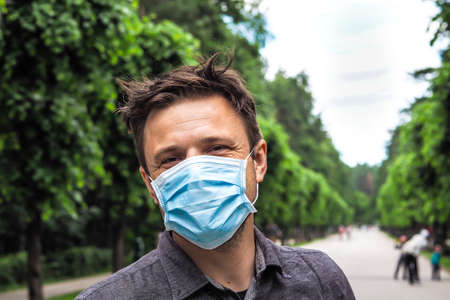 Handsome young European man smiling with a medical face mask on. Closeup of a 35-year-old male in a respirator to protect against Covid-19の写真素材