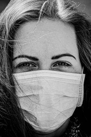 Black and white portrait of beautiful young European woman a medical face mask on to protect against Covid19の写真素材