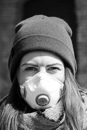 Black and white portrait of beautiful young European woman a medical face mask on to protect against Covid19の写真素材