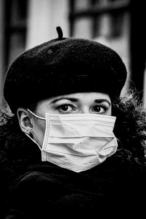 Black and white portrait of beautiful young European woman a medical face mask on to protect against Covid19の写真素材