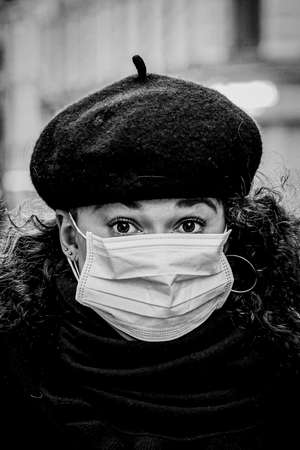 Black and white portrait of beautiful young European woman a medical face mask on to protect against Covid19の写真素材
