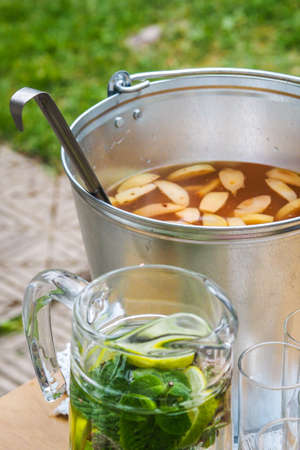 Bucket and jug with cold tea and glasses, summer party in the gardenの写真素材