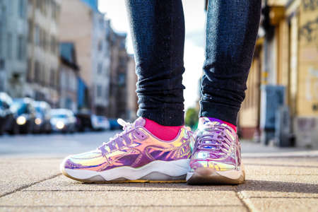 Purple holographic sneakers on a girl legs, with city in the backgroundの写真素材