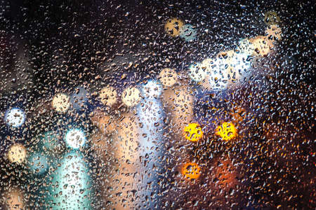 Rainy day, rain drops on window, rainy weather, rain and traffic lights bokeh, traffic jam, defocusedの写真素材