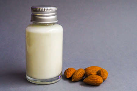 Small glass bottle with almond milk and almondsの写真素材