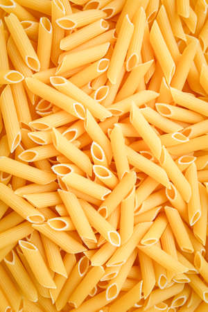 Uncooked penne pasta close up, background. Vertical photoの写真素材