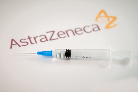 Riga, Latvia: January 12, 2021: AstraZeneca Covid-19 vaccine concept. Close-up of a syringe and and, the AstraZeneca company logo in the background. Defocusedのeditorial素材