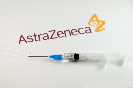 Riga, Latvia: January 12, 2021: AstraZeneca Covid-19 vaccine concept. Close-up of a syringe and and, the AstraZeneca company logo in the background. Defocusedのeditorial素材