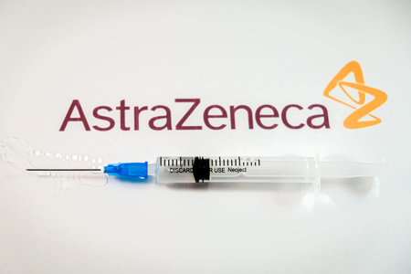 Riga, Latvia: January 12, 2021: AstraZeneca Covid-19 vaccine concept. Close-up of a syringe and and, the AstraZeneca company logo in the background. Defocusedのeditorial素材