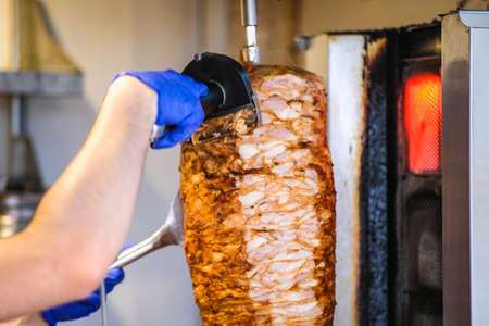 An arm moving to cut the kebab chicken meat. Defocusedの写真素材