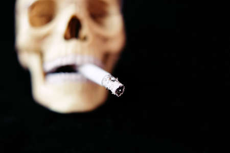 Skull and burning cigarette. Death from smoking concept. Impotence. Defocusedの写真素材