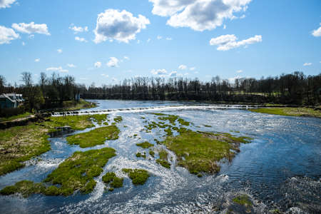 Kuldiga, Latvia - May 1, 2021: Landscape with river, historic brick bridge and Venta River in city Kuldiga, Latviaのeditorial素材