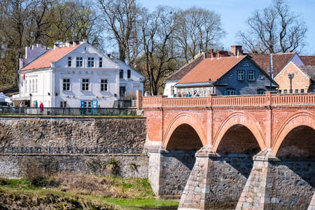 Kuldiga, Latvia - May 1, 2021: Landscape with river, historic brick bridge and Venta River in city Kuldiga, Latviaのeditorial素材