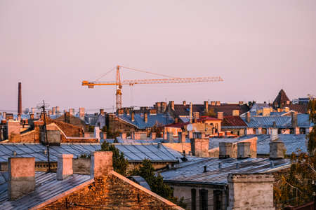 Tower crane on construction site on blue sky background and cityscape. City skyline in morning sunlight. Selective focusの写真素材