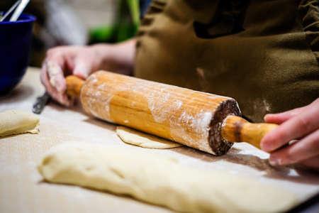 Woman hands rolling out dough in flour with rolling pin in her home kitchen. Selective focusの写真素材