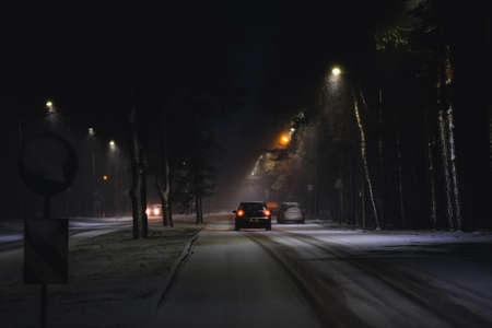 Cars in a snowstorm at night on the road in winter. Traffic in winter. Defocusedの写真素材