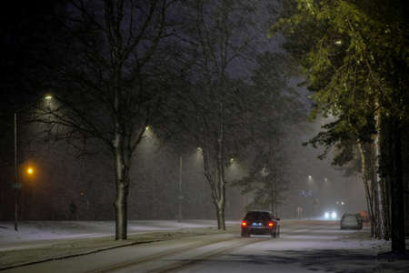 Cars in a snowstorm at night on the road in winter. Traffic in winter. Defocusedの写真素材