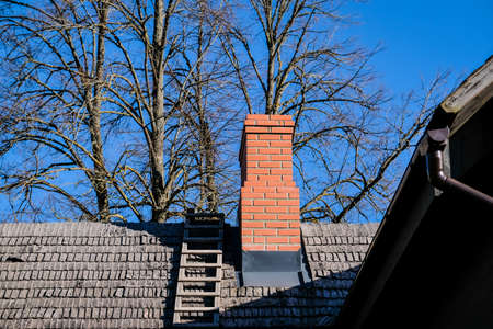 Wooden roof of a detached house with a skylight and red brick chimney against the skyの写真素材