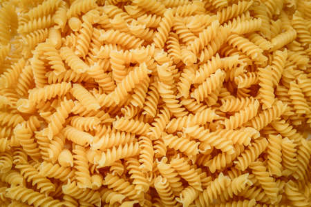 Raw uncooked fusilli pasta, close up background, textureの写真素材