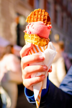 A girl is holding a big tasty ice cream in her hands at a fair in the city. Defocusedの写真素材