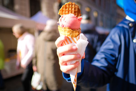 A girl is holding a big tasty ice cream in her hands at a fair in the city. Defocusedの写真素材