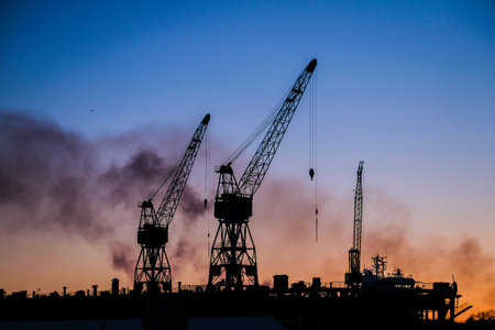Port cranes at sunset. Port, cargo transportation and cargo ships. Selective focusの写真素材