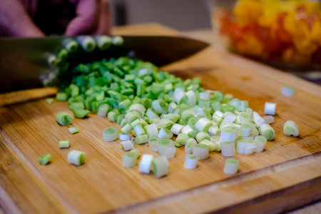 A woman cuts fresh spring onions on a cutting board. Cooking.の写真素材