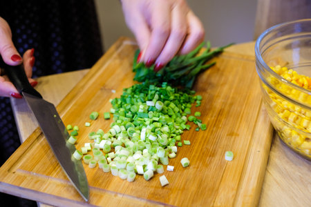A woman cuts fresh spring onions on a cutting board. Cooking.の写真素材
