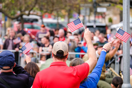 People waving USA flags in a large crowd at a rally
