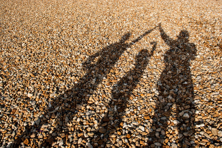 full frame of pebble beach with shadow of 3 peopleの写真素材