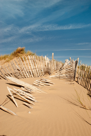 seascape image of three rows of broken fences leading up a sand duneの写真素材