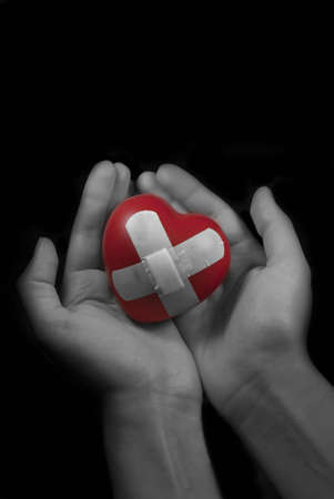 Photo of hands holding a wounded heart. の写真素材