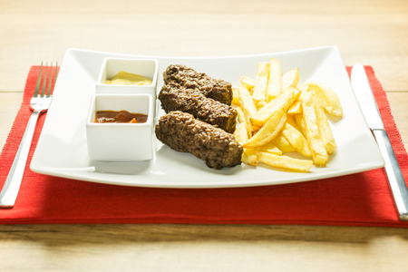 Traditional Romanian Mici And French Fries With Ketchup And Mustard Close Up