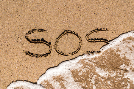 SOS Help Cry For Help Written On Beach Sandの写真素材