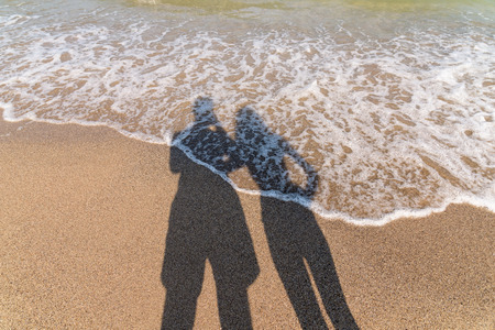 Shadow Of Happy Couple Taking Photos On Beachの写真素材