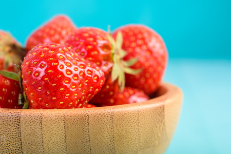 Strawberry Wood Bowl On Blue Boards Backgroundの写真素材
