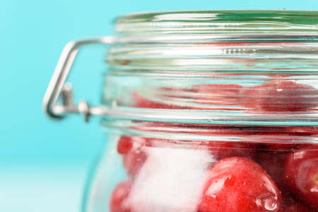 Jar Of Red Fresh Cherries On Turquoise Backgroundの写真素材