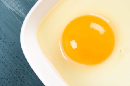 Yellow Egg Yolk In White Bowl On Wood Table