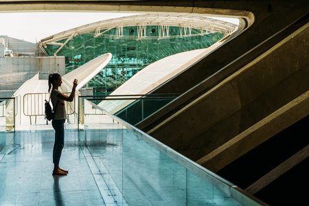 Silhouette Against Light Of Young Woman Taking Photos In Modern Buildingの写真素材