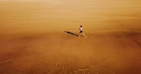 Aerial Drone View Of Healthy Sportive Woman Running On Beach Near Ocean