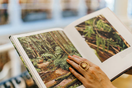 BUCHAREST, ROMANIA - MAY 27, 2018: Woman Wearing Minimalist Contemporary Jewelry Reading Book In Library Storeのeditorial素材