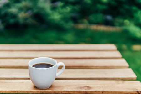 White Coffee Cup On Wooden Table In Green Gardenの写真素材