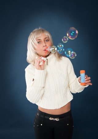 Beautiful woman blowing soap bubbles on a blue backgroundの写真素材