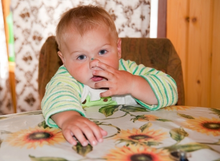 little boy picking his nose at the tableの写真素材