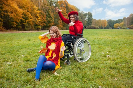 disabled with a friend walking in the autumn Parkの写真素材