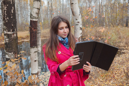girl in the red coat uses the Internet in the Parkの写真素材