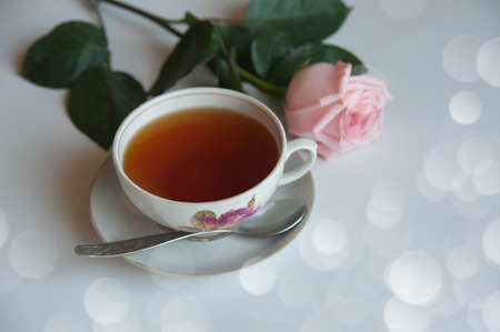 Cup of tea with pink rose with bokehの写真素材