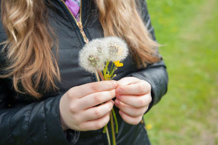 girl in a black jacket holding a white dandelions